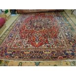 An Heriz carpet, Persian, the madder field with a bold indigo rosette medallion, ivory spandrels,