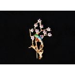 An Italian 18ct gold, enamelled and ruby set brooch, designed as a parrot on a branch with blossom,