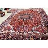 An Heriz carpet, Persian, the madder field with a bold black medallion, ivory and madder spandrels,