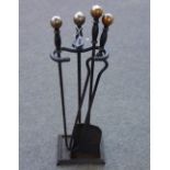 A set of ebonised steel fire tools and stand with spherical brass finials (shovel 70cm),