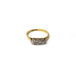 A gold and platinum, diamond set three stone ring, claw set with a row of circular cut diamonds,