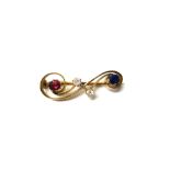 A gold, diamond, ruby and sapphire set brooch, in a scrolling design,