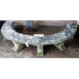 A large composite stone half circular garden bench, the three piece top and seven scroll supports,