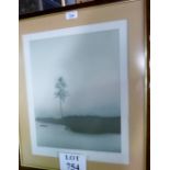 A framed and glazed limited edition print depicting figure in boat with single tree by waters edge