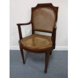 Edwardian mahogany inlaid elbow chair with caned seat and back, on tapering supports and spade feet.