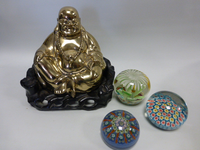 A golden brass Buddha in carved wooden seat, together with three glass paperweights.