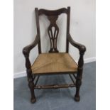 An 18th century elbow chair with pierced back splat and rush seat, on turned front supports.