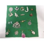 Twelve silver brooches including one pendant/brooch, four silver pendants and a silver charm,