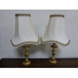 Pair of decorative brass table lamps with cream shades, approx 51cms in height.