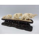 Early 20thC Ivory carved procession of four elephants on 20cm long carved wooden stand with pierced