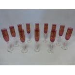 Set of twelve unidentified Ruby glass Champagne flutes with gilded decoration,