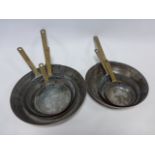 Set of seven graduated copper pans with brass handles.