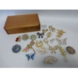 Carved wooden box containing twenty one assorted brooches.