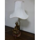 Table lamp with seated semi-clad gilded figure on a circular marble plinth, with cream shade,