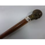 A walking cane with bronze knop in the form of a broad smiling gentleman.