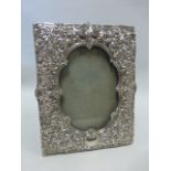 Silver photograph frame with embossed foliate decoration and vacant cartouches,