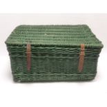 Large green painted 20thc wicker basket with leather straps and raised on wooden supports.