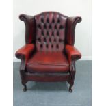 Leather wing back armchair with button back and studded detailing.