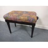 Adjustable height polished oak piano stool with upholstered seat.