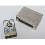 A brass match box with enamelled lid with image of a girl in bodice and shorts worn in the