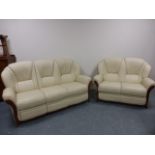 Two and three seater cream leather sofas, the three seater with hidden foot rest.