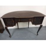 Semi circular table with single frieze drawer flanked by side cupboards each with carved fronts,