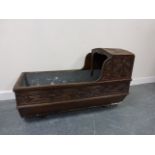 A 19thC carved oak crib with later linin