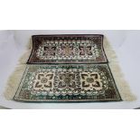 TWO SMALL EASTERN SILK TABLE RUGS with stylized floral designs, fringed, 63cm x 32cm