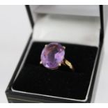 A GOLD COLOURED METAL SET SINGLE STONE DRESS RING set with an oval amethyst, shank stamped 9ct, size