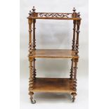 A VICTORIAN WALNUT THREE TIER WHATNOT having pierced gallery top, raised on ring turned supports