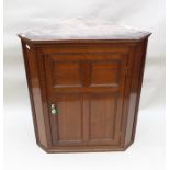 A GEORGE III OAK HANGING CORNER CUPBOARD fitted single quarter panelled door opening to reveal plain