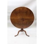 A GEORGE III OAK SNAP TOP SUPPER TABLE on turned stem and arched triform supports, 88cm diameter