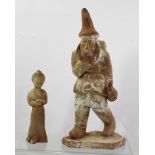 A CHINESE POTTERY FIGURE of a foreign merchant with baggage, wearing a pointed hat, holding a