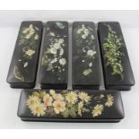 A SUITE OF FIVE RECTANGULAR JAPANNED PAPIER MACHE PEN CASES, each painted with daisies, other