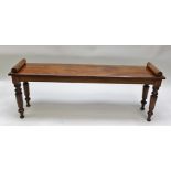 A 19TH CENTURY MAHOGANY HALL BENCH/WINDOW SEAT having turned ends raised on turned and tapering