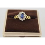 AN 18CT GOLD SAPPHIRE AND DIAMOND CLUSTER RING, having white gold oval claw head with sapphire and