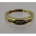 A DIAMOND AND GOLD COLOURED METAL SET HALF ETERNITY RING, having channelled head set with seven