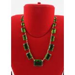 A NAPIER GREEN GLASS FAUX PERIDOT NECKLACE of faceted trap cut stones, each claw set, 40cm long