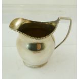 ATKIN BROTHERS A GEORGIAN STYLE SILVER MILK JUG, having baluster plain body, gadroon wire rim and