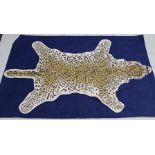 A NEPALESE WOOLWORK WALL HANGING/RUG, spread leopard pelt stylised design on a blue background,