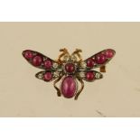 AN EDWARDIAN STYLE GOLD COLOURED METAL SET RUBY AND DIAMOND BROOCH fashioned as a butterfly with ten