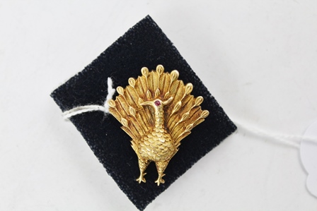 A RUSSIAN GOLD COLOURED METAL BROOCH, fashioned as a peacock with single red stone eye and tooled