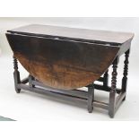 A PART GEORGE III OAK OVAL DROPLEAF DINING TABLE, raised on ring turned gateleg frame supports, with