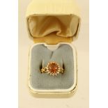 A GOLD COLOURED METAL DRESS RING set with amber tourmaline, bordered with seventeen diamonds on a