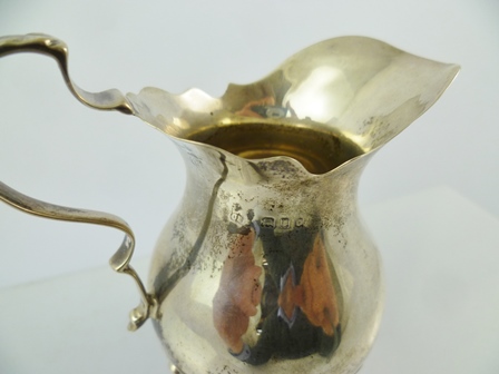 C**E** A GEORGIAN STYLE SILVER CREAM JUG having cut wavy rim, bulb shape body, raised on three - Image 2 of 2