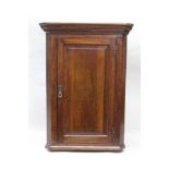 A GEORGE III OAK HANGING CORNER CUPBOARD with fitted single fielded panel door with brass H