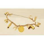 A GOLD CURB LINK CHARM BRACELET having bolt ring clasp and nine charms including a 1910 gold half