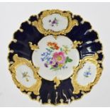 A DRESDEN PORCELAIN ORNAMENTAL PLATE, having vignettes of flora, blue ground and gilt edging, 24cm