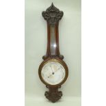 A LATE VICTORIAN CARVED OAK CASED BAROMETER AND THERMOMETER, main calibrated dial 19cm diameter,