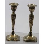 ** & S (obscured) A PAIR OF PRESSED AND FILLED SILVER CANDLESTICKS, each having square canted stem